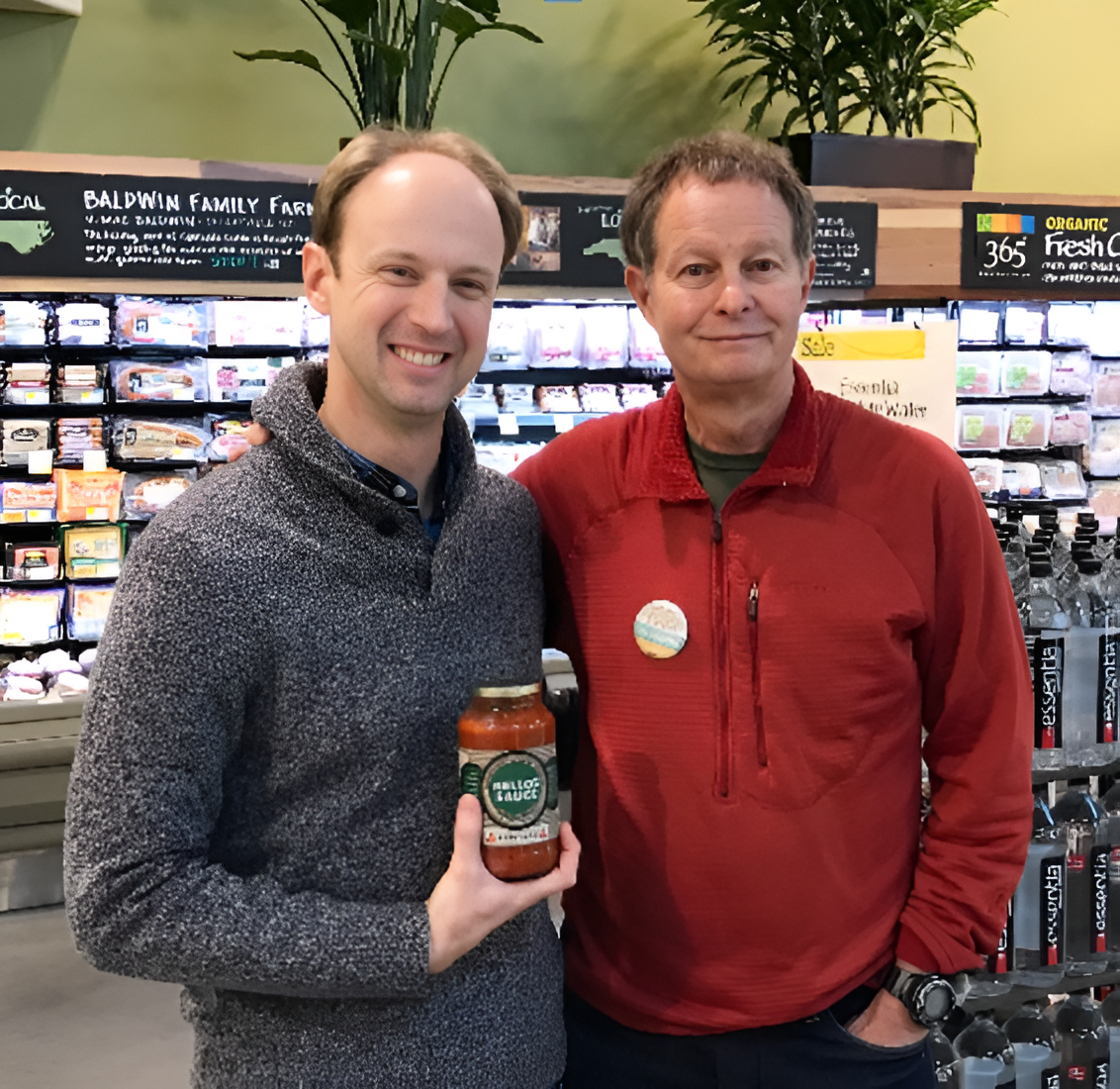 Neal McTighe, founder of Arithmis, with John Mackey at Whole Foods Market — holding a jar of Nello's Sauce